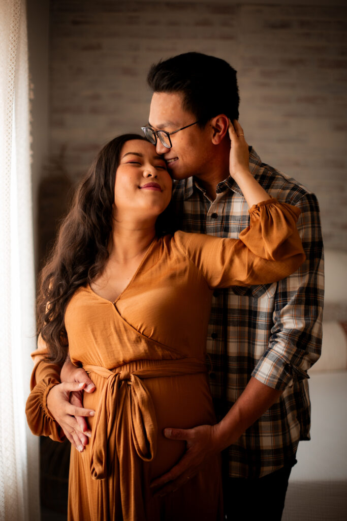 couple expecting baby, hold each other tenderly during maternity session