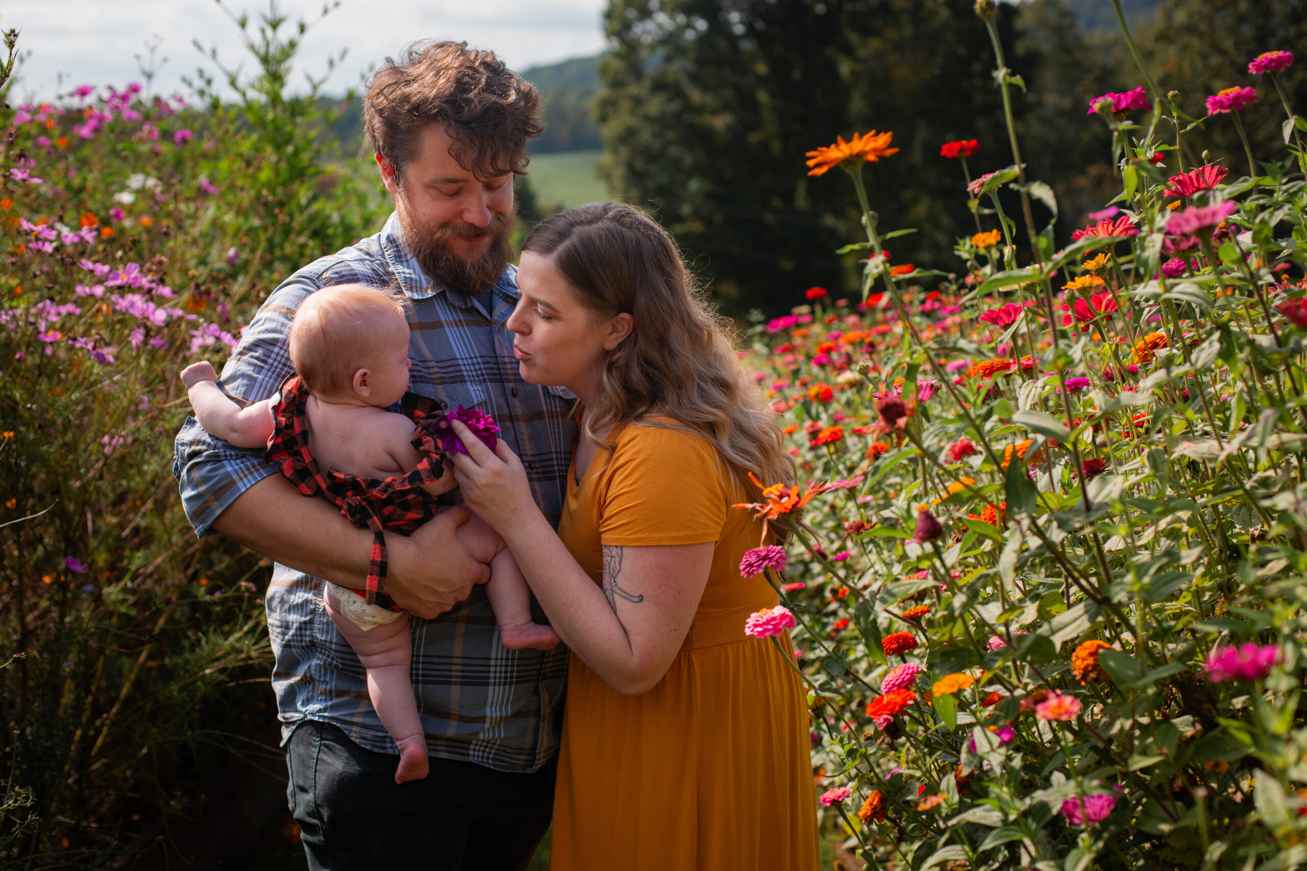 family of three, parents with infant amongst flowers